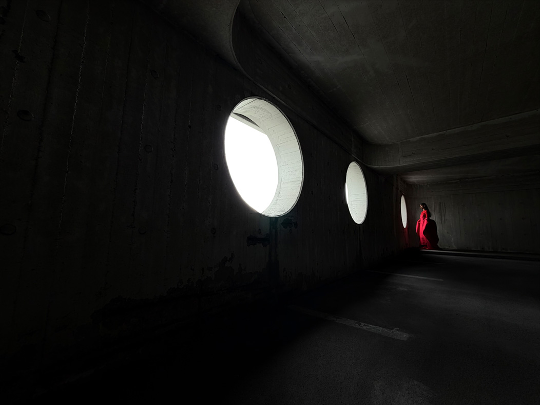 Жінку в довгій червоній сукні фотографують у порожній кімнаті. Додаток «Фотографії» демонструє можливості професійної системи камер, перемикаючись між такими фокусними відстанями: 200 мм, 100 мм, 48 мм, 35 мм, 28 мм, 13 мм і макрозйомка