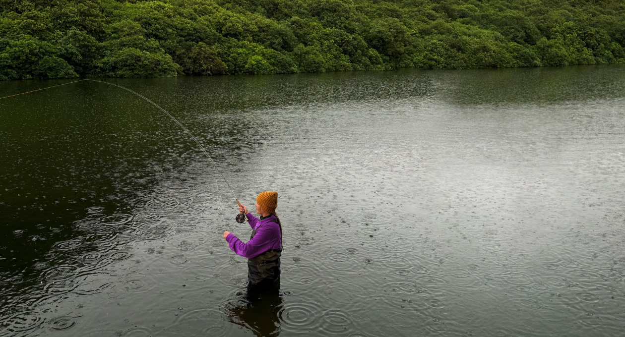 Photo of a woman fly-fishing in a lake, Pixelmator Pro tool removing unwanted object in the background being highlighted in yellow
